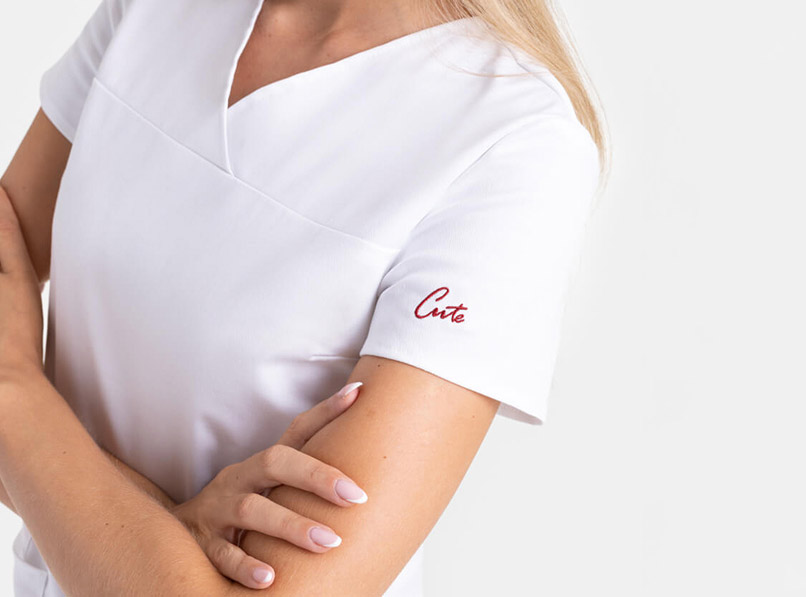 Žena nosi plavu uniformu sa prošivenim logotipom